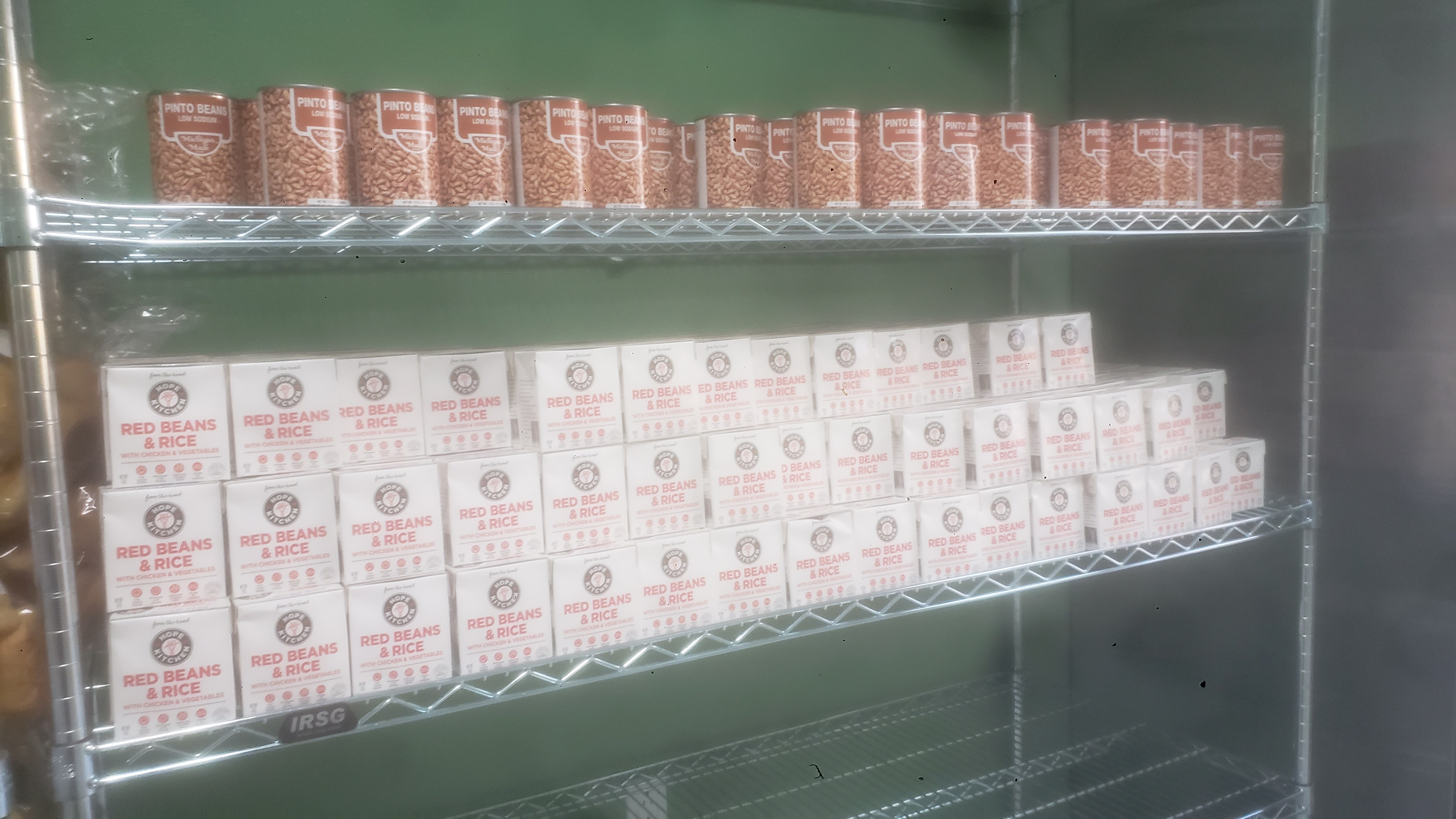 Cans of pinto beans on one shelf and boxes of red beans amd rice on the other.